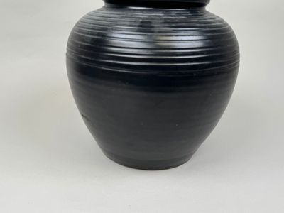 a black vase that is sitting on a white surface
