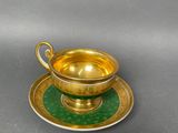 an image of a gold cup and saucer on a green plate