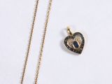 two necklaces with a heart shaped pendant on a white surface