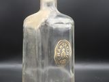 an image of a clear glass bottle with a gold emblem