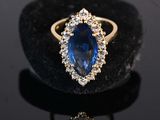 a close up of a blue sapphire and diamond ring on a black surface