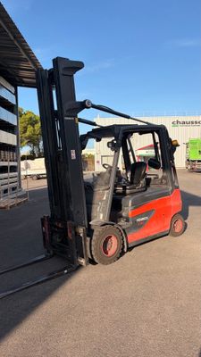 a red forklift truck parked in front of a building