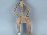 figurine en bois représentant un homme assis sur une chaise, une cigarette à la bouche
