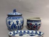 trois pièces de poterie bleue et blanche sont posées sur une table
