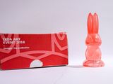 un petit lapin en plastique posé à côté d'une boîte rouge
