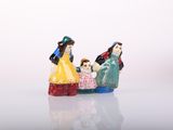 three figurines of people sitting on a white surface