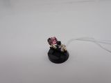 a small pink and white ring on a black stand