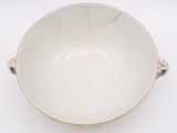 a white bowl sitting on a table with a handle