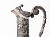 a silver and glass pitcher with a handle on a table