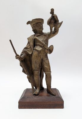 statue en bronze représentant un homme tenant un oiseau, avec un autre oiseau posé sur un socle en bois