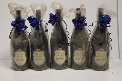 six bottles of wine wrapped in plastic with blue ribbons