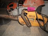 a yellow chainsaw sitting on the floor next to a pink sign