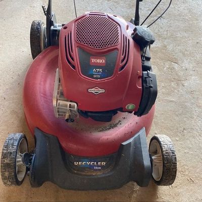 une tondeuse à gazon rouge posée par terre dans le garage