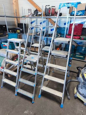 de nombreuses échelles empilées dans un garage