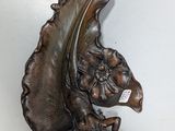 a bronze sculpture of a bird on a wall