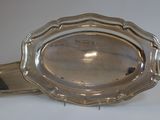 an antique silver plate with a handle on a white surface
