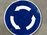 un panneau circulaire bleu et blanc sur lequel figurent des flèches