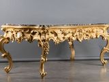 a gold table with a marble top on a grey floor