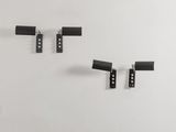 trois pièces en métal noir sont accrochées à un mur, à côté d'un mur blanc