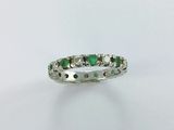a close up of a white gold ring with emerald stones