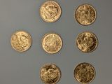 six pièces d'or sont disposées en cercle sur une surface grise
