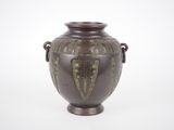 un vase marron orné de motifs verts sur un fond blanc