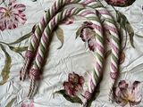 a white and pink floral bed spread with a rope