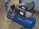 a blue air compressor sitting on the floor in a room