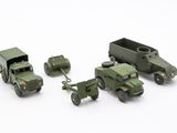 three toy army vehicles and a truck on a white surface
