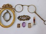 un cadre doré avec un miroir, une paire de lunettes, une paire de ciseaux et une paire de lunettes de vue
