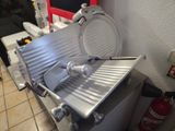 une grande trancheuse à viande posée sur un plan de travail dans une cuisine