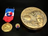 une médaille d'or, une médaille et un insigne posés sur une table