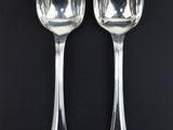 two silver spoons on a black surface with a black background