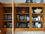 un placard sur lequel sont posés de la vaisselle et des tasses, dans la cuisine
