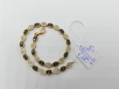 un bracelet en or orné de pierres noires et blanches sur fond blanc