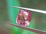quelqu'un tient une pince sur laquelle est monté un diamant rose