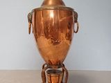 a large copper urn on a wooden stand