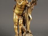 une figurine antique en bronze représentant un Cupidon tenant un oiseau