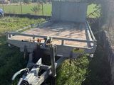 a trailer that is sitting in the grass near a tree