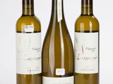 trois bouteilles de vin posées les unes à côté des autres sur une surface blanche