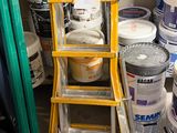 several buckets of paint and a ladder in a room