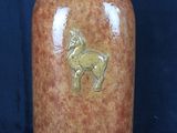 un vase marron orné d'un cheval sur fond bleu
