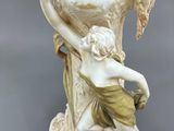 a white vase with a statue of a boy holding a flower