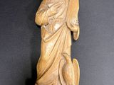 une statue en bois représentant une femme tenant un oiseau, posée sur une table