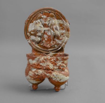 un vase orange et blanc posé sur un socle en métal