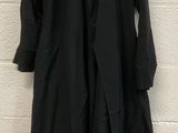 a black coat hanging on a white brick wall next to a white brick wall