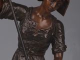 bronze statue of a woman holding a cane and a hat