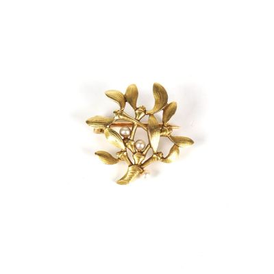 un gros plan d'une broche en or ornée de feuilles