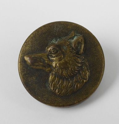 un gros plan d'un bouton en métal orné d'une tête de chien