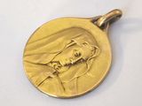 gold medal of a woman with a veil on her head